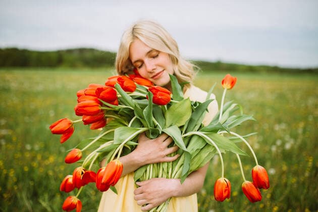 Creative Highlights Symbolbilder Content female in dress standing with bunch of red tulip flowers in meadow in summer with closed eyes CamilleGirard_GirlWithTulips_18.jpg Copyright: xCamillexGirardx Model Released
