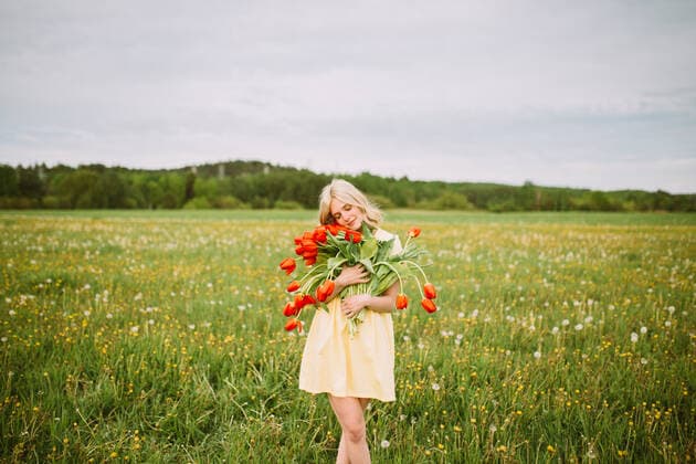 Content female in dress standing with bunch of red tulip flowers in meadow in summer with closed eyes CamilleGirard_GirlWithTulips_19.jpg Copyright: xCamillexGirardx Model Released