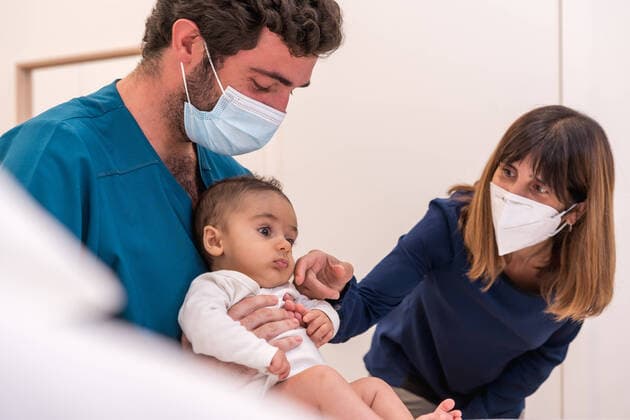 Male pediatrician in mask examining baby in medical room with mother during appointment in modern hospital, Model released, Property released UnaiHuici_BaleaMikelAndJavi_15.jpg Copyright: xUnaixHuicix MR
