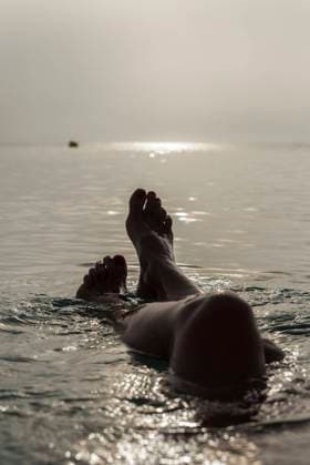 Crop barefoot legs of unrecognizable female lying in sea water and enjoying sunny morning during vacation on Playa de Muro VictorPrieto_SummerMorning_10.jpg Copyright: xVictorxPrietox Model Released