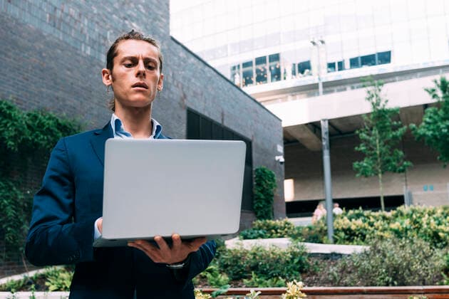 IMAGO Creative: Klimawandel - Zukunft und Innovation Businessman using laptop while standing in park model released Symbolfoto ASGF00815