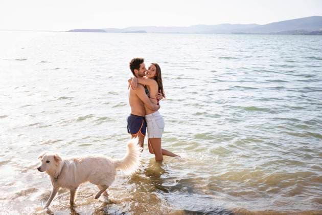 Smiling couple embracing while standing by dog in lake model released Symbolfoto property released EIF01720