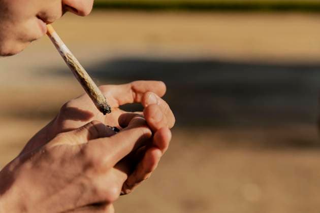 Teenage boy igniting marijuana joint during sunset model released Symbolfoto ACPF01266