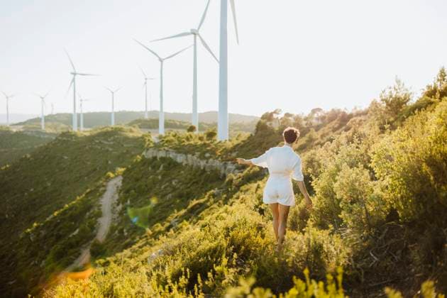 Woman walking towards wind turbines on mountain during sunset model released Symbolfoto GMCF00190