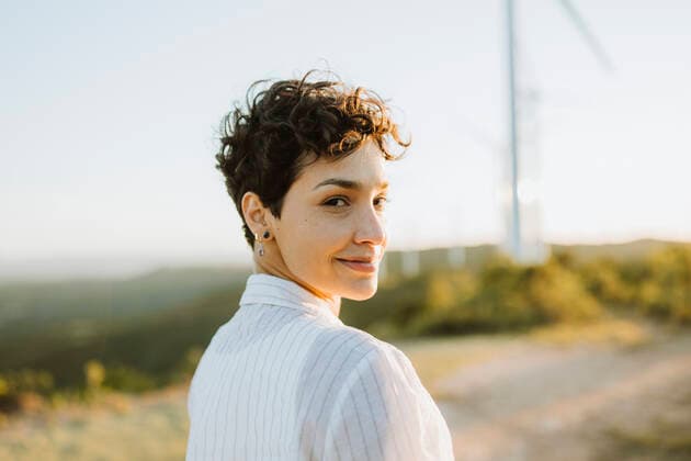 Smiling mid adult woman looking over shoulder during sunset model released Symbolfoto GMCF00203