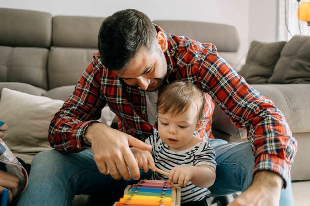 IMAGO Creative: Vaterschaft Father teaching xylophone to son in living room model released Symbolfoto property released GMCF00228