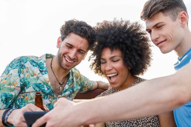 IMAGO Creative: Landleben - Alfresco, Draußen Cheerful male and female friends sharing smart phone during weekend party model released Symbolfoto property released IFRF00998