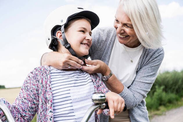 IMAGO Creative: Gesellschaft, Integration Smiling woman putting cycling helmet to girl while standing by bicycle model released Symbolfoto UUF24172