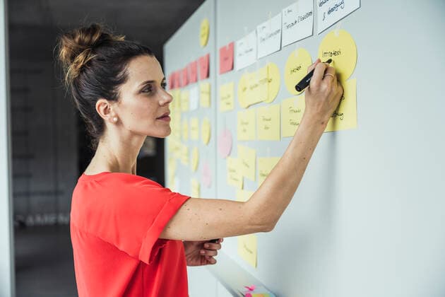 IMAGO Creative: Bildung, Schreiben Businesswoman writing on adhesive note while working in office model released Symbolfoto property released UUF24427