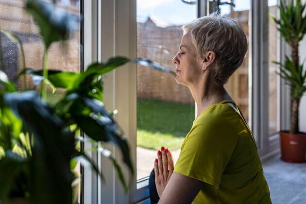 IMAGO Creative: Internationaler Frauenmonat, Gesundheit, Frauen in der Menopause Mature woman meditating with hands clasped at home model released Symbolfoto property released WPEF05094