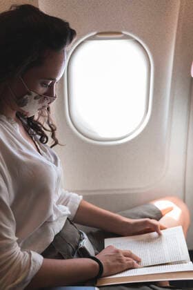 IMAGO Creative: 2021 Trends Businesswoman reading book while traveling in airplane during COVID-19 model released Symbolfoto JAQF00696