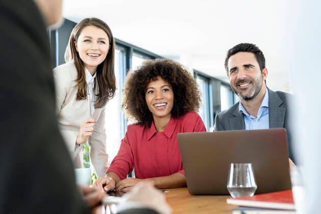 Smiling colleagues with laptop attending meeting at office model released Symbolfoto property released PESF03002
