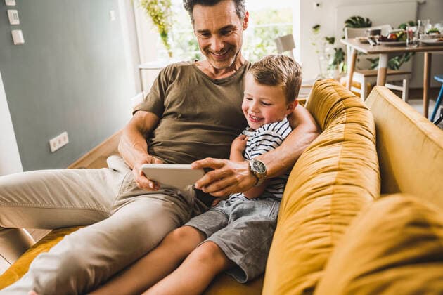 IMAGO Creative: Jahreszeit Winter, Fantasievoll drinnen spielen Man sitting with son on sofa while using smart phone at home model released Symbolfoto property released UUF24527
