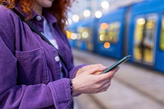 Woman using mobile phone at tram station model released Symbolfoto WPEF05073