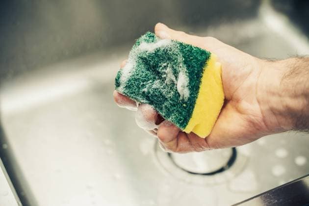 17 May 2021: Man with sponge and detergent cleans sink under running water *** Mann mit Schwamm und Spülmittel reinigt Waschbecken unter fließend Wasser