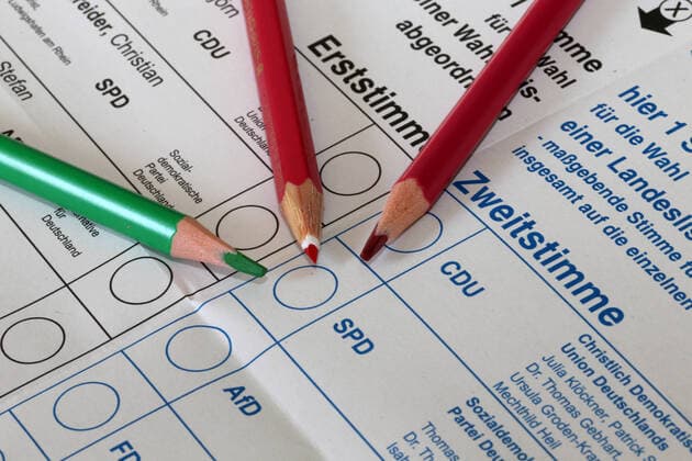 Symbolbild Rot-Rot-Grün: Stimmzettel für die Bundestagswahl am 26. September 2021 mit zwei roten und einem grünen Buntstift
