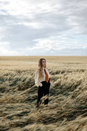 Side view of young mindful female in formal wear with tie looking away among spikes in countryside, Model released AlbertoOrtega_BertaWheatField_20.jpg Copyright: xAlbertoxOrtegax MR