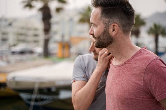 IMAGO Creative: Urban Diversity Content couple of homosexual men in t shirts embracing while looking away in harbor, Model released AnnaUlman_GayCouple_8.jpg Copyright: xAnnaxUlmanx MR