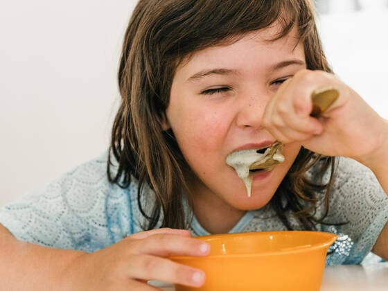 IMAGO Creative: 2021 Favoriten IMAGO Creative: Clickbait, Rezepte und Kochen Adorable child eating delicious cream soup from plastic bowl while sitting at table during lunch at home, Model released HodeiUnzueta_TwinsEating_28.jpg Copyright: xHodeixUnzuetax MR