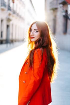 Side view of stylish female with ginger hair and in vivid orange suit walking in the city street looking at camera JakeJakab_MariaPortraits_17.jpg Copyright: xJakexJakabx Model Released