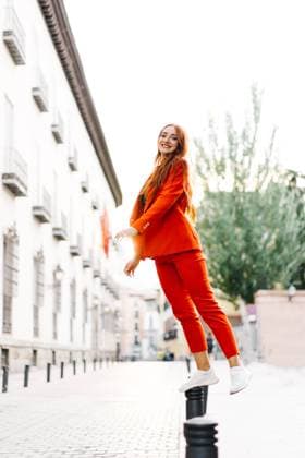 IMAGO Creative: Clickbait, Modetrends Side view of redhead female in bright orange suit standing on metal parking bollard in street and looking at camera JakeJakab_MariaPortraits_22.jpg Copyright: xJakexJakabx Model Released