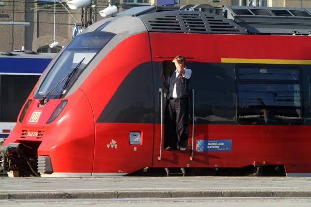 Lokführer der DB Deutsche Bahn schaut aus der Tür des Führerstand s eines Triebzug s im Hauptbahnhof München, Bayern, Deutschland *** DB Deutsche Bahn train driver looking out of the door of the driver s cab of a multiple unit train at Munich central station, Bavaria, Germany