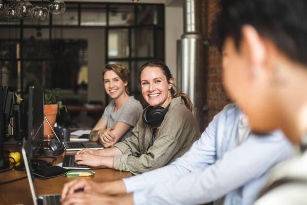 Happy male and female colleagues talking while working at startup company Sweden, Stockholm, model released, property released Copyright: xMaskotx , MA87899