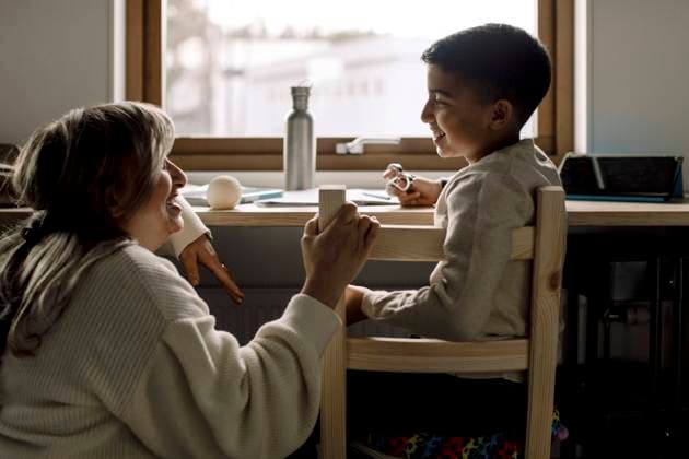 Smiling son talking with mother while sitting on chair at home Sweden, Stockholm, model released, property released Copyright: xMaskotx , MA88375