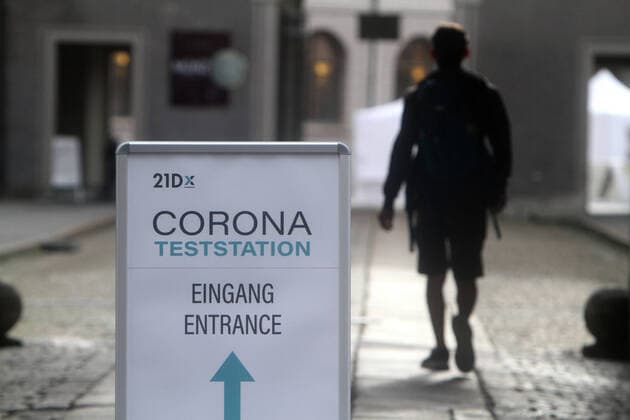 Aufsteller mit Richtungspfeil und Aufschrift 21D Corona Teststation steht in der Innenstadt von München. Ein Mann geht zum Test, Bayern, Deutschland