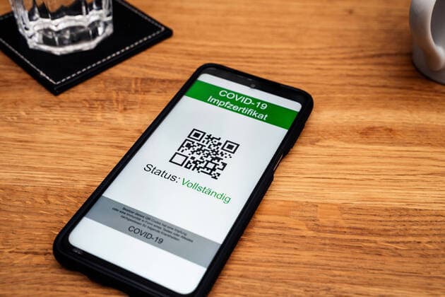Digitaler Impfpass, Zertifikat über vollständige Impfung EU Grüner Pass oder Immunität durch genesung oder Test nach 2G und 3G Regel auf dem Bildschirm einens Smartphones auf dem Tisch in einem Restaurant