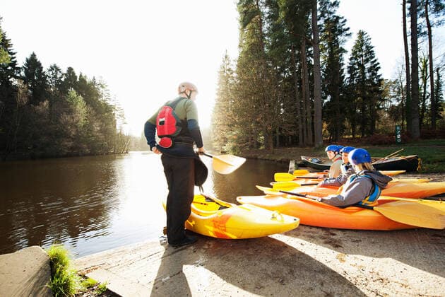 IMAGO Creative: Landleben - Alfresco, Draußen Kayaks lined up at edge of lake, 09.07.2012, Copyright: xNickxDalyx wearing,explaining,learning,teaching,holding,recreation,paddle,full length,head and shoulders,adventure,challenge,preparation,guidance,protection,safety,skill,togetherness,getting away from it all,nature,mature adult,45 to 49 years,20 to 24 years,caucasian ethnicity,multi-ethnic group,woman,mature man,small group of people,occupation,outdoors,riverbank,rural,lake,river,day,helmet,life jacket,environment,sitting,standing,sunlight,leisure,kayaking,travel,journey,vacation,transport,kayak,instructor,oar,remote,small group,both male and female,Conversation,Explanation,Sitting,Standing,Teaching,Thinking,Learning,Holding,Caucasian Ethnicity,Multi-Ethnic Group,Mature Adult,45-49 Ref:45nk0029rf