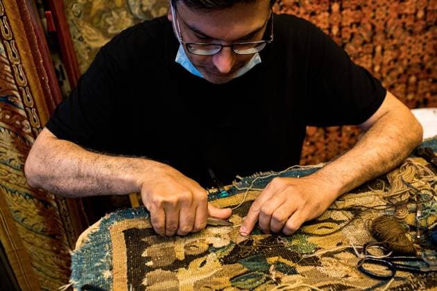 Paris Flea Market Saint-Ouen, France on 18 July 2021. An antique dealer restores a carpet in his shop at the Biron market in the Saint-Ouen flea market. Many restorers give new life to some antiques on the spot. Paris Seine Saint-Denis France fohlen-parisfle210718_npHOi  Copyright: xEmericxFohlenx