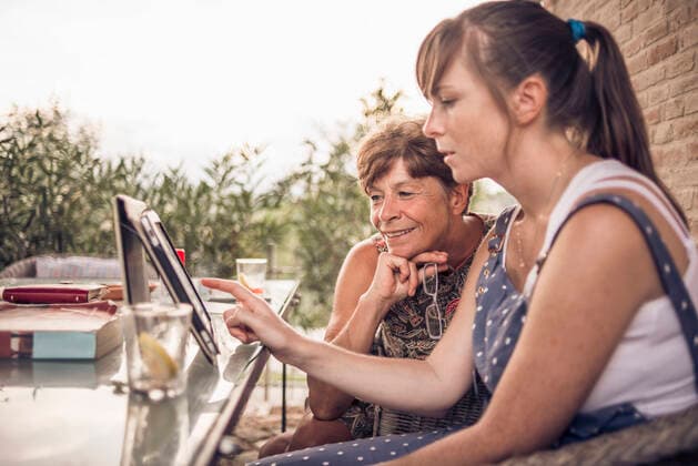 IMAGO Creative: Landleben, Digitalisierung auf dem Land Mother and mid adult daughter looking at digital tablet, 27.01.2014, Copyright: xPeterxSchiazzax, model released, wearing,looking,watching,using,differential focus,side view,waist up,retirement,aging,connections,real people,bonding,quality time,sharing,togetherness,contented,happiness,love,table,30 to 34 years,60 to 64 years,caucasian ethnicity,female,woman,mid adult woman,senior woman,two people,house exterior,outdoors,garden,rural,field landscape,summer,day,casual clothing,dungarees,vest,communication,sitting,smiling,family,daughter,mother,digital tablet,lifestyle,sunlight,family life,portability,wifi,networking,relationship,enjoyment,touch screen,February 2014 Release,buildings,Sitting,Watching,Caucasian Ethnicity,Mid Adult,30-34 Year Ref:IS09AG0CX