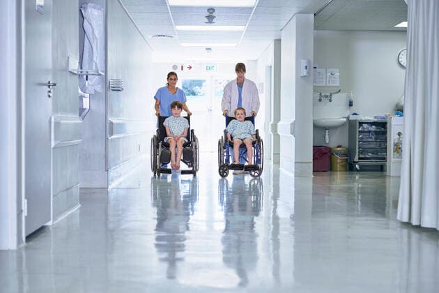 Medical orderly pushing boy patients in wheelchair on hospital children s ward, 05.07.2016, Copyright: xFrankxandxHelenax, model released, , property released, wearing,pushing,working,front view,full length,childhood,responsibility,bonding,care,cooperation,innocence,skill,teamwork,trust,on the go,25 to 29 years,child,caucasian ethnicity,mixed race ethnicity,multi-ethnic group,woman,young woman,boy,colleague,four people,medical occupation,nurse,patients,indoors,hospital,examination gown,lab coat,surgical scrubs,illness,medical,pediatrics,transport,wheelchair,6 to 7 years,health service,patient,both male and female,healthcare,medical orderly,9 to 10 years,July 2016 Release,childrens ward,Pushing,Working,Caucasian Ethnicity,Mixed Race Perso Ref:IS09AZ9GC
