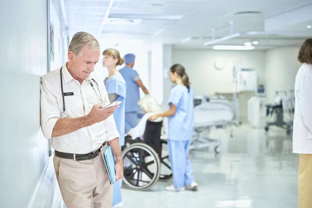 Senior doctor reading smartphone message in hospital ward, 15.09.2016, Copyright: xFrankxandxHelenax, model released, , property released, wearing,reading,using,working,gray hair,authority,concentration,connections,responsibility,active seniors,cooperation,skill,teamwork,text message,confidence,stethoscope,70 to 74 years,caucasian ethnicity,mixed race ethnicity,multi-ethnic group,mature woman,young woman,senior man,five people,medical occupation,doctor,indoors,south africa,hospital,hospital ward,medical clothing,shirt,protective clothing,trousers,communication,technology,medicine,alerting,both male and female,smartphone,health-and-safety,paarl,healthcare,update,smart-casual,September 2016 Release,Dialing,Text Messaging,Reading ,Thinking,C Ref:IS09B23VT
