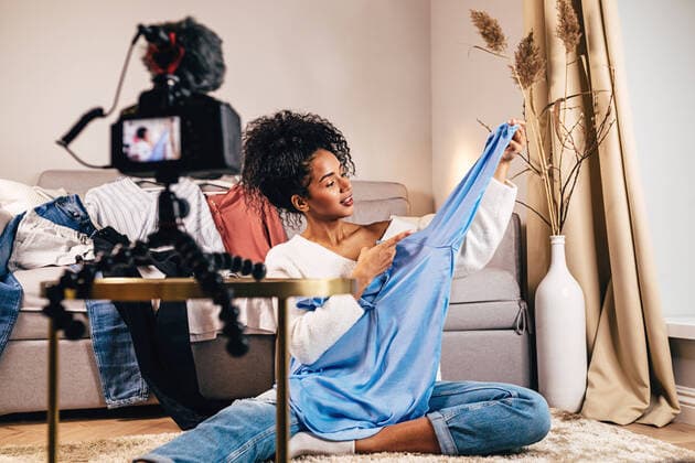 IMAGO Creative: Digitale Welt, Social Commerce Fashion vlogger recoding video about casual shirt in living room Copyright: xxArtemxVarnitsinx