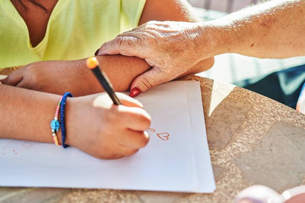 IMAGO Creative: Gesellschaft, Integration From above of crop unrecognizable grandmother touching arm of anonymous granddaughter sitting at table and drawing on paper in sunny day, Model released AdalbertoRodriguez_GrandmotherAndGranddaughter_6.jpg Copyright: xAdalbertoxRodriguezx MR