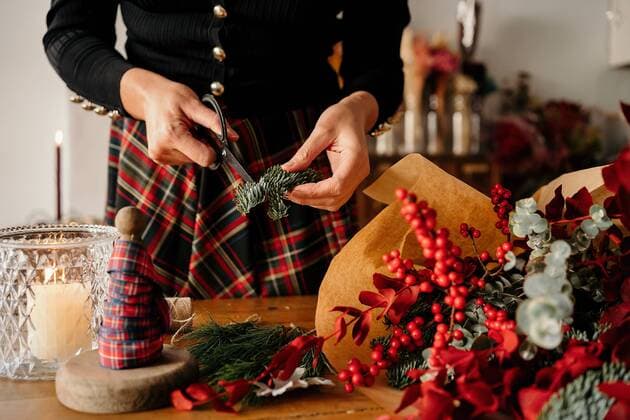 Crop unrecognizable female florist standing and cutting twigs of fir while arranging Christmas bouquet on wooden table, Model released, Property released GustavoPozo_ChristmasDecoration_31.jpg Copyright: xGustavoxPozox MR