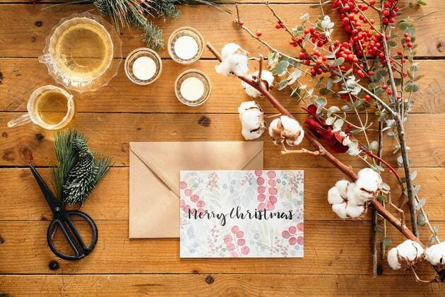 Top view of Christmas composition with colorful postcard with inscription Feliz Navidad placed near burning candles and cups of tea on wooden table decorated with colorful branches of plants, Property released GustavoPozo_ChristmasDecoration_54.jpg Copyright: xGustavoxPozox Model Released
