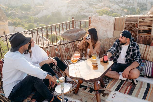 From above of female taking picture of young couple on instant photo camera while having cocktails in bar with friends in terrace in Cappadocia, Turkey, Model released, Property released JordiBataller_SunsetBar_18.jpg Copyright: xJordixBatallerx MR