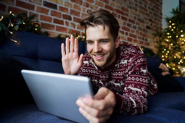 IMAGO Creative: Jahreszeit Winter, Couching Smiling man waving hand to video call through digital tablet in living room model released Symbolfoto property released ABIF01632
