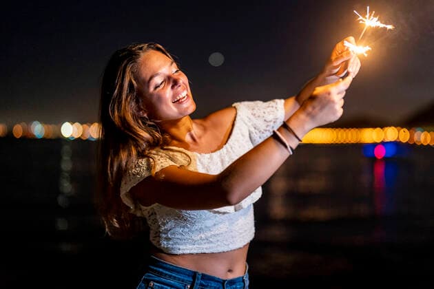 Cheerful young woman enjoying with sparklers at night model released Symbolfoto DLTSF02183