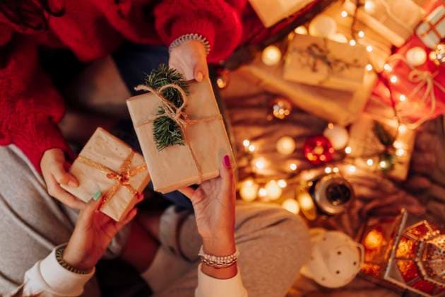 Young female friends giving Christmas present to each other at home model released Symbolfoto property released EGHF00179