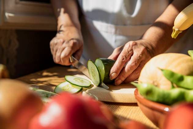 Senior woman cutting cucumber in kitchen model released Symbolfoto ACPF01299