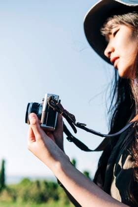 Young woman wearing hat photographing through camera during sunny day model released Symbolfoto ASGF01245