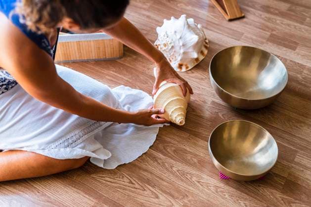 Female sound therapist with seashell sitting on hardwood floor model released Symbolfoto property released DLTSF02128