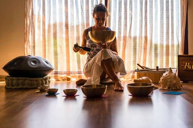 Female sound therapist holding brass bowl while sitting in front of window model released Symbolfoto property released DLTSF02131