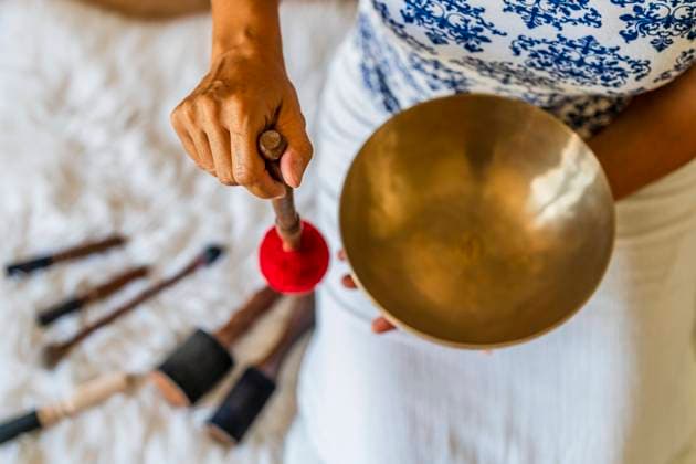 Female sound therapist playing brass bowl with mallet in studio model released Symbolfoto property released DLTSF02136