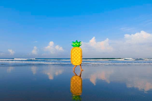 Woman with pineapple float walking at beach model released Symbolfoto EAF00114