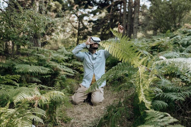 IMAGO Creative: Klimawandel - Zukunft und Innovation Man using virtual reality headset while kneeling in forest model released Symbolfoto property released JCCMF03788